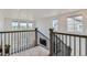 An upstairs hallway with wrought iron railings, plush carpet, and bright natural light streaming through multiple windows at 14551 Hudson St, Thornton, CO 80602