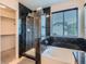 Bathroom with a black tiled shower and bathtub combo, natural light, and a walk-in closet at 5553 Jasper St, Denver, CO 80239