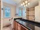 Bathroom featuring a large mirror, black countertop, vanity, and a shower with tile surround at 5553 Jasper St, Denver, CO 80239
