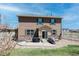 A two-story home with stone accents, a small patio, green shutters, landscaping, and a grassy lawn at 2177 Shadow Creek Dr, Castle Rock, CO 80104