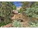 Landscaped backyard with a rock water feature, mature trees, and stone path, enhancing outdoor appeal at 8259 Nola Dr, Denver, CO 80221