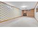 Spacious basement with a brick fireplace, carpeted floors, and wallpapered accent walls at 8259 Nola Dr, Denver, CO 80221