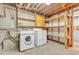 Laundry room with washer, dryer, and wooden shelving at 8259 Nola Dr, Denver, CO 80221