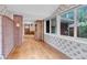 Inviting sun room with hardwood floors, brick accent wall and bright windows at 8259 Nola Dr, Denver, CO 80221
