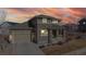 Attractive home with a stone facade, covered porch, and two-car garage, set against a dramatic sunset backdrop at 3925 W 149Th Ave, Broomfield, CO 80023