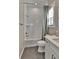 Bright bathroom with white tiled shower, gray floor tiles, and white vanity with quartz top at 11464 Stonewash St, Littleton, CO 80125