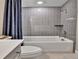 Clean bathroom with white tub and toilet with nice grey shower and tile walls at 11464 Stonewash St, Littleton, CO 80125