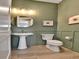 Modern powder bathroom featuring green walls, a round mirror and elegant fixtures at 11464 Stonewash St, Littleton, CO 80125