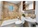 Well-lit bathroom features a bath tub with shower, tiled walls, and vanity with a mirrored medicine cabinet at 404 S Jasmine St, Denver, CO 80224