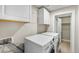 Laundry room featuring modern white washer and dryer and overhead cabinets for organized storage at 1655 Yates St, Denver, CO 80204