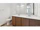 Bathroom features double sink vanity with brown cabinets and modern hardware, toilet, and large mirror at 18951 E 96Th Pl, Commerce City, CO 80022
