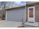 A gray two-car garage door with brick siding on a sunny day at 17912 E Milan Pl, Aurora, CO 80013