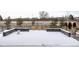 Backyard patio is covered in snow with a stone half-wall overlooking the street at 533 Red Thistle Dr, Highlands Ranch, CO 80126