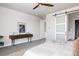 Bright bedroom featuring carpet floors, ceiling fan, rustic console table, and barn door to bathroom at 533 Red Thistle Dr, Highlands Ranch, CO 80126