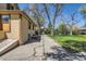 Backyard exterior with mature trees, a paved path, and ample space for landscaping at 5475 W 1St Ave, Lakewood, CO 80226