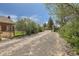Gravel driveway, mature trees providing privacy to this home's approach at 5475 W 1St Ave, Lakewood, CO 80226
