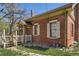 A well-maintained brick house featuring a cozy porch, decorative shutters, and a lush lawn at 5475 W 1St Ave, Lakewood, CO 80226