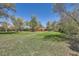 A large yard with mature trees and landscaping features a red fence at 5475 W 1St Ave, Lakewood, CO 80226