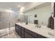 Modern bathroom featuring a double sink vanity, large mirror, and tiled shower with glass door at 15646 W Floyd Dr, Morrison, CO 80465