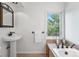 Bathroom featuring pedestal sink, soaking tub, and a window with verdant views at 160 Bristlecone Way, Boulder, CO 80304