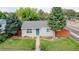 Charming single-story home featuring a well-manicured lawn, mature trees, and a welcoming blue front door at 103 S Zenobia St, Denver, CO 80219