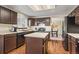 Well-lit kitchen featuring dark cabinets, an island, and modern appliances at 5481 E 117Th Ave, Thornton, CO 80233