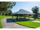 A picnic pavilion with tables and benches sits on a green lawn near a paved trail under a sunny blue sky at 5481 E 117Th Ave, Thornton, CO 80233