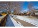 A neighborhood trail with a wood fence, bare trees, and a light dusting of snow alongside a row of suburban houses at 5481 E 117Th Ave, Thornton, CO 80233