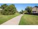 A sunny neighborhood trail with a concrete path, green lawns, mature trees, and a wood fence line at 5481 E 117Th Ave, Thornton, CO 80233