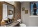 Stylish powder room with bronze mirror and faucet with dark vanity and decorative tiled accent wall at 5625 Twilight Way, Parker, CO 80134