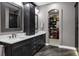 Bathroom featuring double vanities, dark wood cabinets, and an arched entrance to a walk-in closet at 5625 Twilight Way, Parker, CO 80134