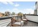 Outdoor balcony with wooden chairs overlooking city views on a sunny day at 3520 W Connejos Pl # 5, Denver, CO 80204