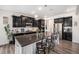 Modern kitchen featuring black cabinetry, stainless steel appliances, and a large island with seating at 11346 Kittredge St, Commerce City, CO 80022