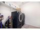 Well-lit laundry room with modern washer and dryer, storage shelves, and cleaning supplies at 11346 Kittredge St, Commerce City, CO 80022