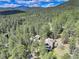 An aerial view of the property shows the home nestled among the tall trees of the surrounding forest at 30221 Marge Ln, Evergreen, CO 80439