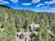 An aerial view reveals the home situated within a dense forest setting with surrounding mountain vistas at 30221 Marge Ln, Evergreen, CO 80439