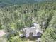 A bird's eye view shows a home nestled among towering trees in a lush forest setting at 30221 Marge Ln, Evergreen, CO 80439