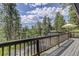 Inviting deck offering serene views of towering pines and a spacious seating area with shade umbrella at 30221 Marge Ln, Evergreen, CO 80439