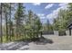 Ample driveway and fenced parking area nestled among mature pine trees, offering privacy and natural beauty at 30221 Marge Ln, Evergreen, CO 80439
