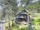 Gorgeous two-story home nestled in the trees, featuring a wraparound deck and stone accents at 30221 Marge Ln, Evergreen, CO 80439