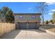 Two-car garage with modern gray doors and exterior lighting, along with a paved driveway and partial fence at 900 S Webster St, Lakewood, CO 80226