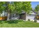 Charming gray home featuring a well-manicured lawn, inviting front porch, and mature shade tree at 11760 Eudora Ct, Thornton, CO 80233