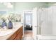 Bathroom with a dual sink vanity, shower with glass door, and doorway to a bedroom at 2028 Ulster St, Denver, CO 80238