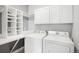 Bright laundry room with white washer, dryer, built-in shelving, and ample storage space at 2028 Ulster St, Denver, CO 80238