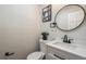 Powder room with white vanity, modern faucet, and round mirror at 12807 Garfield Cir, Thornton, CO 80241