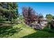 Landscaped backyard with grassy area, mature trees, and brick retaining wall at 3792 E Briarwood Ave, Centennial, CO 80122