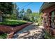 Landscaped backyard with brick retaining wall, mature trees, and a patio area at 3792 E Briarwood Ave, Centennial, CO 80122