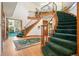 Grand foyer featuring a split staircase, wooden banisters, green carpet runner, hardwood floors and high ceilings at 1332 Meadow Trl, Franktown, CO 80116