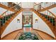 Elegant foyer with split staircase, hardwood floors and a view into the living room with fireplace at 1332 Meadow Trl, Franktown, CO 80116