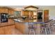 Bright kitchen with a large center island with seating, wooden cabinets, black appliances, and hardwood floors at 1332 Meadow Trl, Franktown, CO 80116